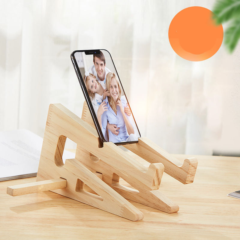 Compact wooden holder supporting a smartphone alongside a laptop on a workstation